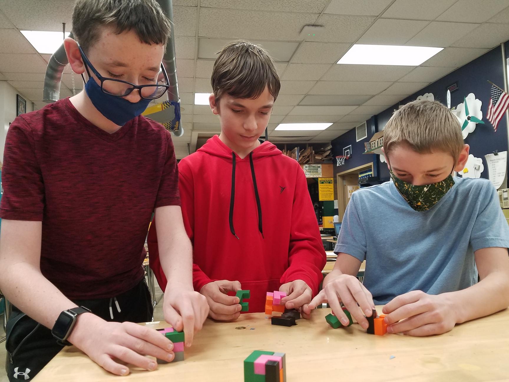 Andrew Baker, Jason Whitefield, and Collin Dransart perform a final fit of their 3-D printed puzzles