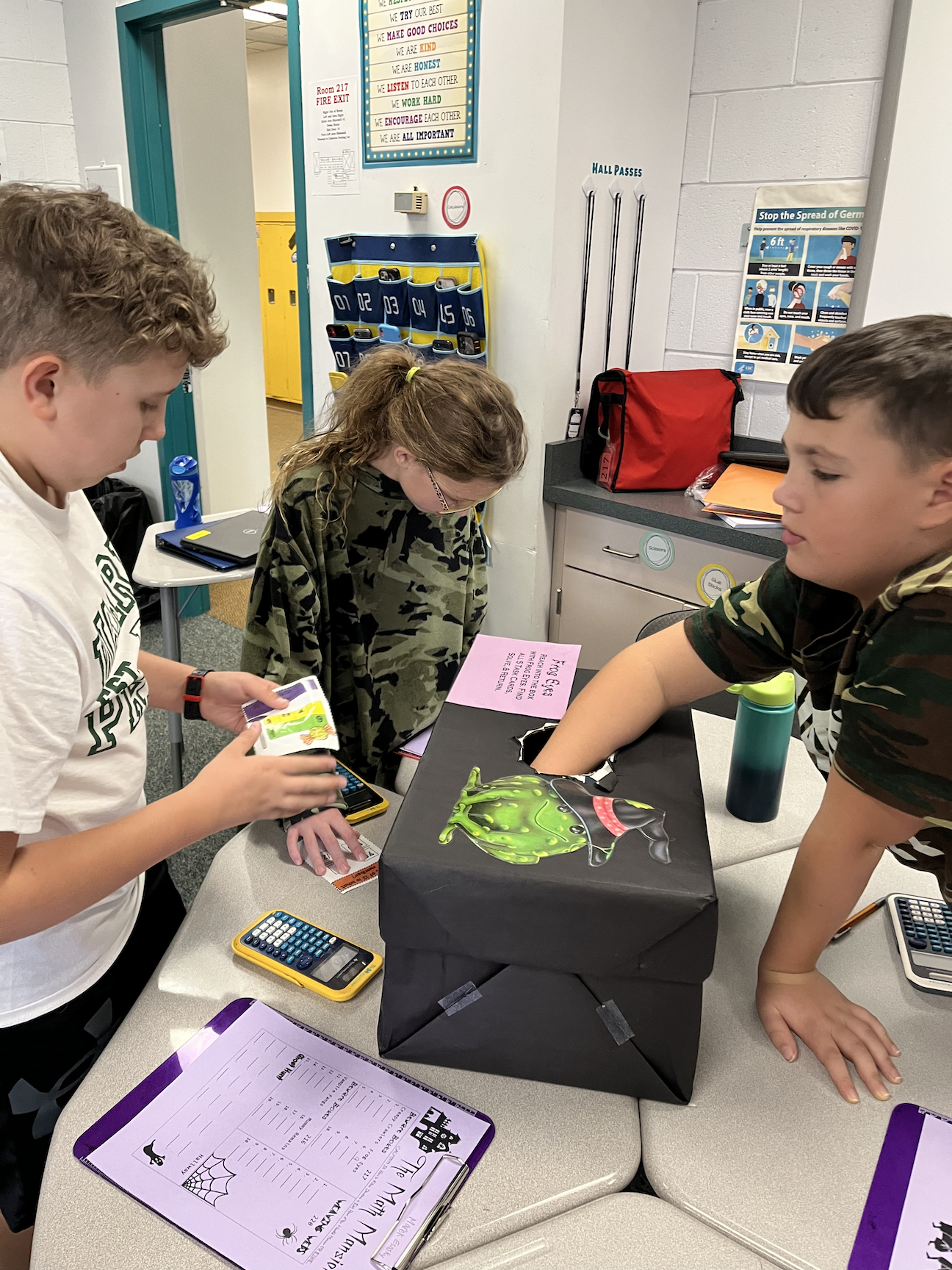 6th-graders Marek Esasky, Ezza Lapcevic, and Nolan Yeager search for math problems in the Beware Boxes